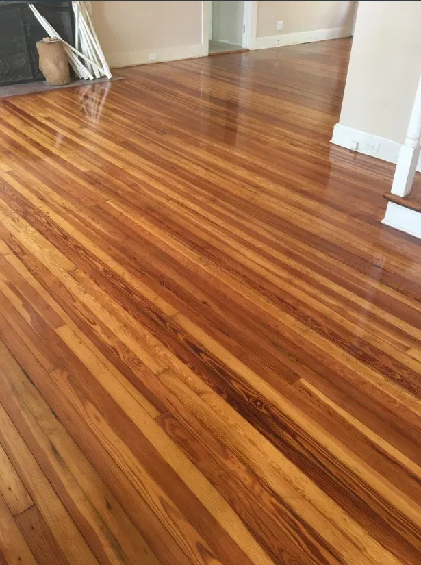 Polished hardwood floor in empty room with white trim and beige walls